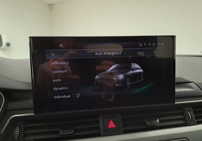 Écran central affichant le menu Audi drive select avec une image 3D grise Daytona de l'Audi A4 Avant vue de profil droit.