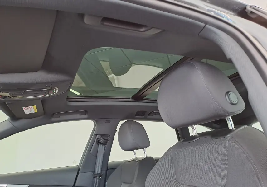 Vue intérieure du toit panoramique en verre et des sièges avant noirs de l'Audi A4 Avant Gris Daytona 2024.