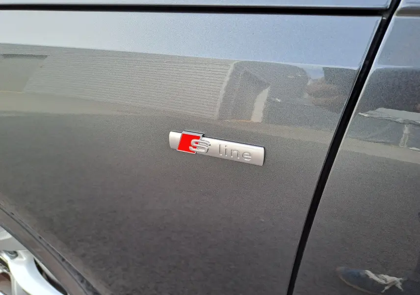 Gros plan sur l'emblème S line sur la porte côté gauche d'une Audi A4 Avant 2024 gris Daytona métallisé.