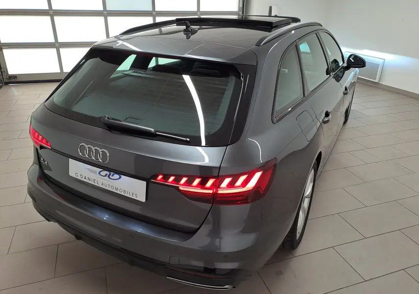 Audi A4 Avant 40 TDI gris Daytona vue 3/4 arrière droit avec feux arrière allumés et toit ouvrant panoramique