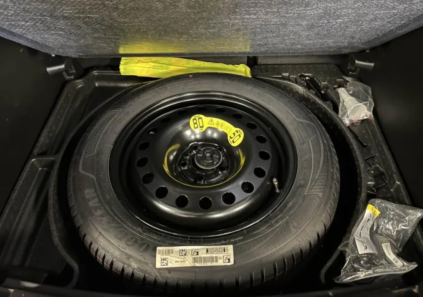 Roue de secours temporaire noire dans le coffre du Jeep Compass 2024, version hybride essence Altitude.