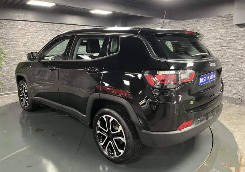 Jeep Compass noir en 3/4 arrière droit, jantes alliage noires et argent, dans un showroom intérieur moderne.
