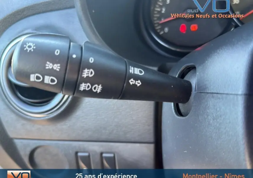 Gros plan sur la manette des phares et clignotants du tableau de bord d'un Dacia Lodgy blanc 2018.