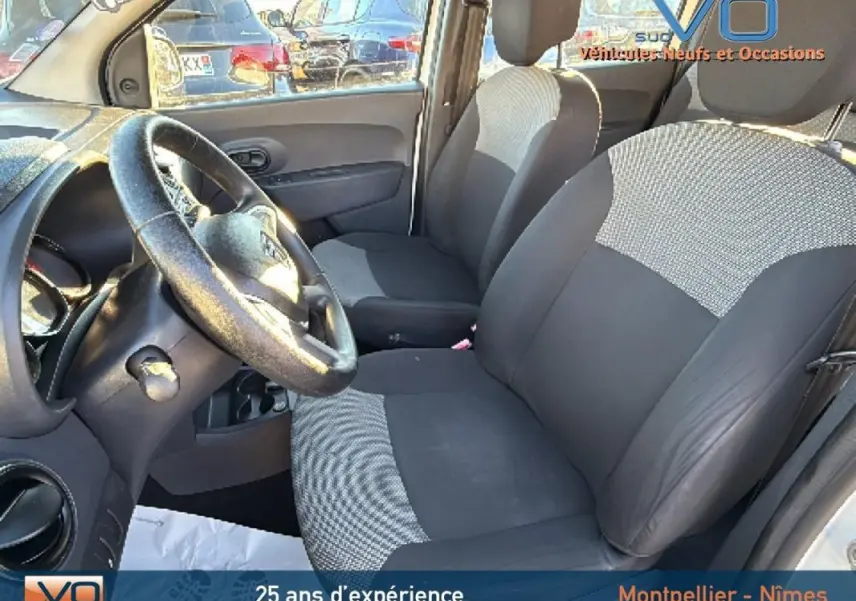 Vue intérieure côté conducteur du Dacia Lodgy blanc 2018, mettant en valeur les sièges avant en tissu bicolore et le volant.