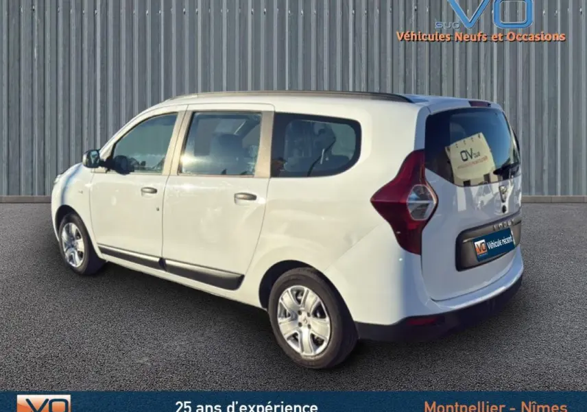 Vue 3/4 arrière droite d'un Dacia Lodgy blanc avec barres de toit et vitres teintées arrière.
