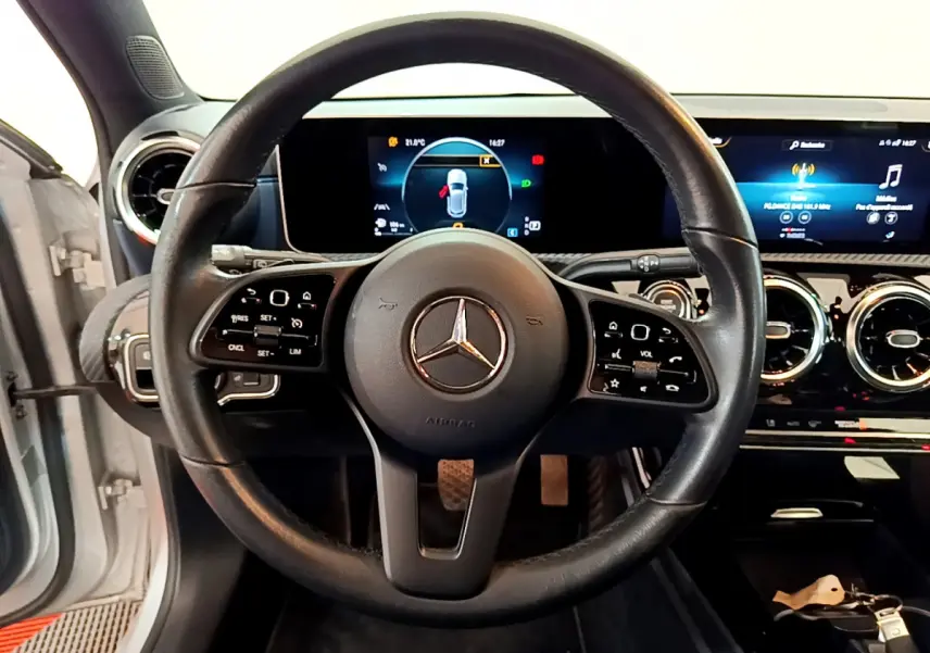 Vue rapprochée du volant cuir noir et du tableau de bord numérique d'une Mercedes Classe A gris clair 2020.