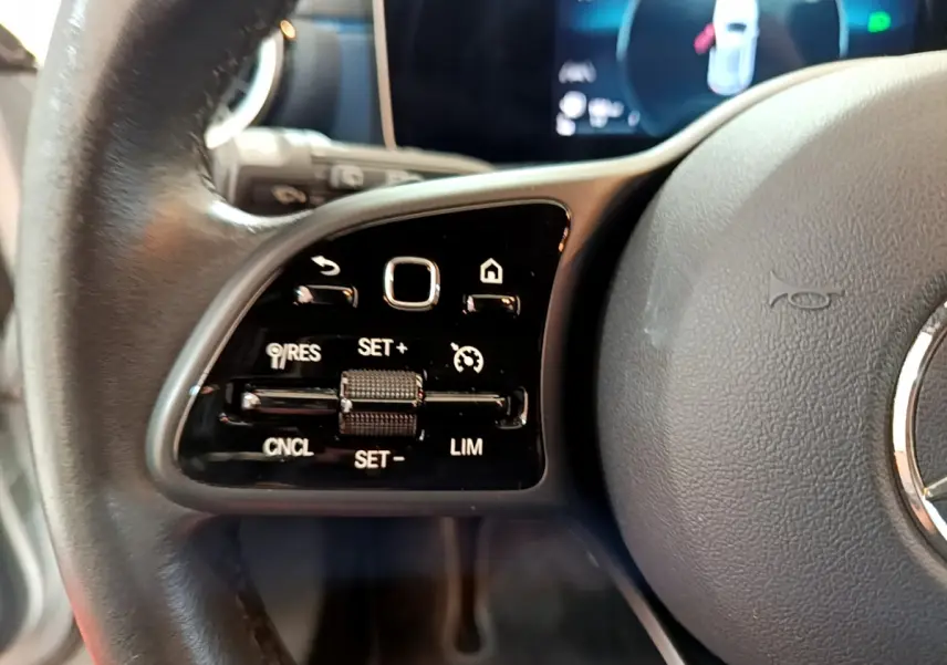 Gros plan sur les commandes à gauche du volant cuir d'une Mercedes Classe A 180 d Business Line 2020.