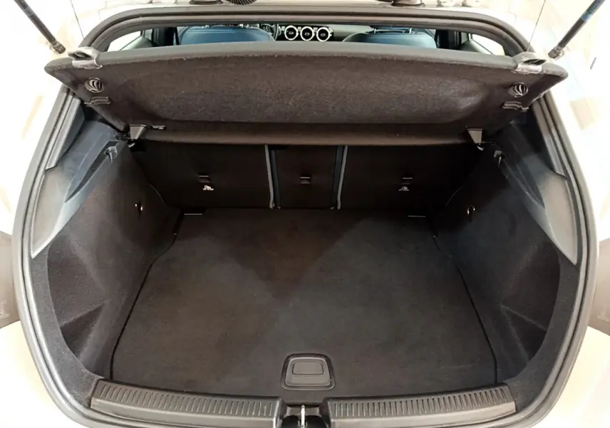 Coffre ouvert vu de l'arrière d'une Mercedes Classe A gris clair, montrant un espace de chargement propre et spacieux.