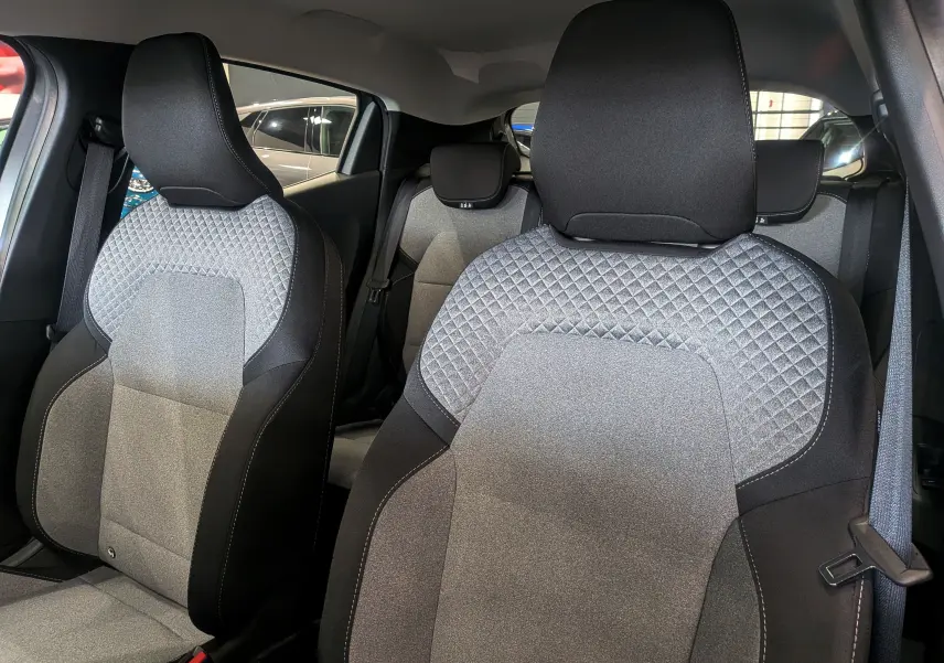 Gros plan sur les sièges avant en tissu gris et noir de la Renault Clio V Blue dCi 100 CH Evolution, intérieur moderne.