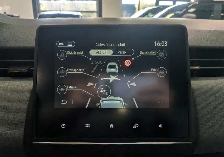 Écran tactile central de la Renault Clio V gris schiste montrant les aides à la conduite et alertes en interface digitale.