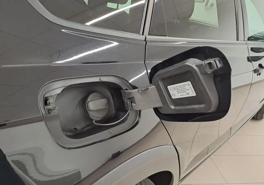 Gros plan sur la trappe à carburant ouverte côté gauche d'un Volkswagen Taigo noir intense nacré, essence.