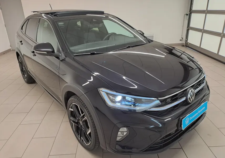 Volkswagen Taigo noir intense nacré en 3/4 avant droit avec toit ouvrant électrique ouvert en intérieur showroom.