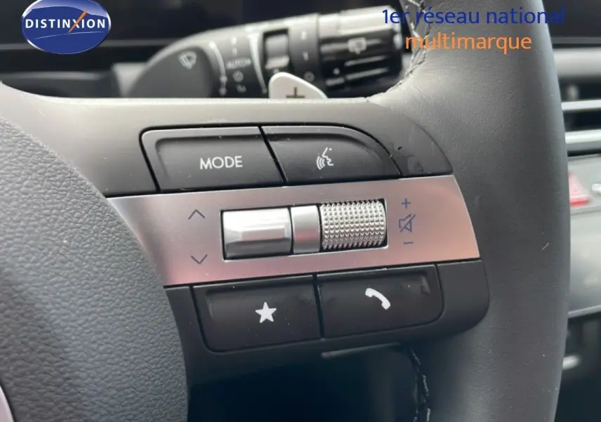 Gros plan sur les commandes gauche du volant noir du Hyundai Tucson blanc Atlas, avec molette et boutons multifonctions.