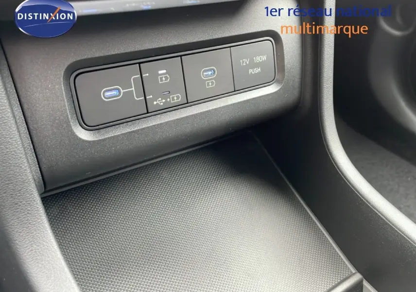 Détail intérieur du Hyundai Tucson 2026 montrant les ports USB et prise 12V sur la console centrale noire.