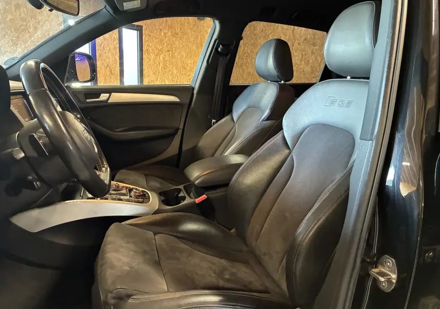 Vue intérieure côté conducteur de l'Audi SQ5 noir, sièges sport en cuir avec logo SQ5 embossé sur appuie-tête.