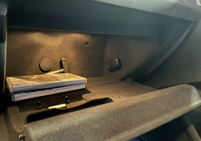 Vue intérieure du vide-poche passager de l'Audi SQ5 noir, avec manuels et éclairage ambiant doux.