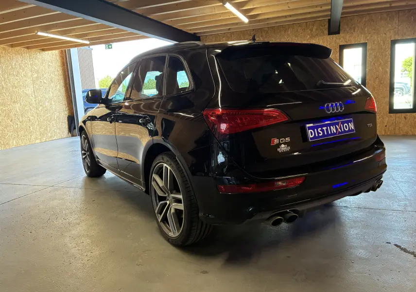 Audi SQ5 noir vue 3/4 arrière droit, avec jantes alu, double sortie d'échappement chromée et becquet arrière.