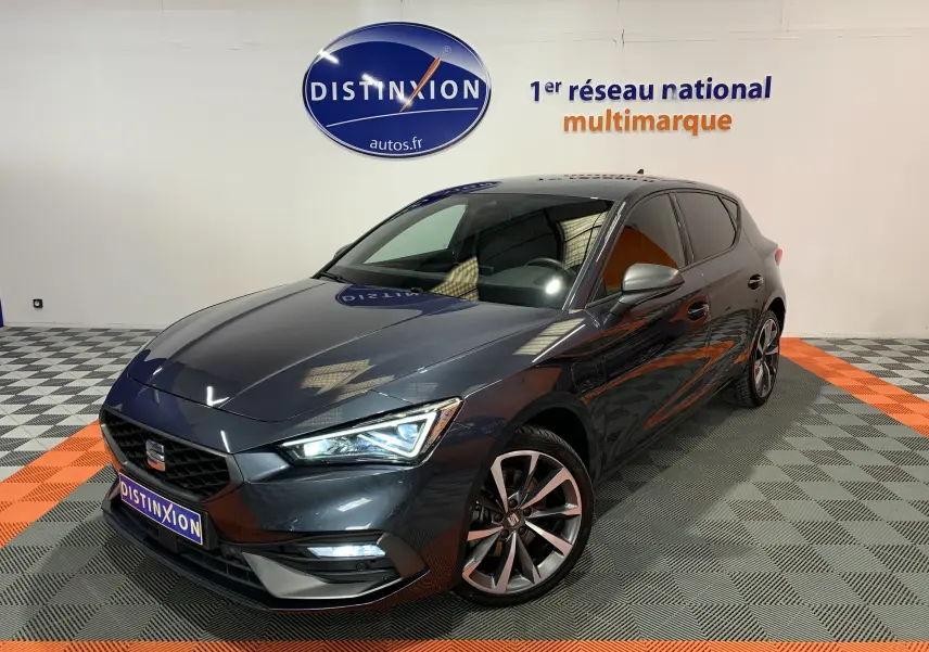 Vue 3/4 avant droite d'une SEAT Leon E-HYBRID 204 FR gris métallisé avec jantes alliage et phares LED allumés