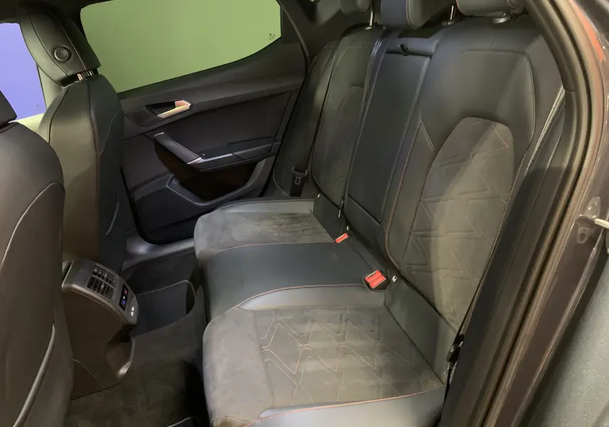 Vue intérieure arrière droite de la SEAT LEON E-HYBRID 204 FR DSG6 avec sièges noirs en cuir et alcantara à surpiqûres orange.