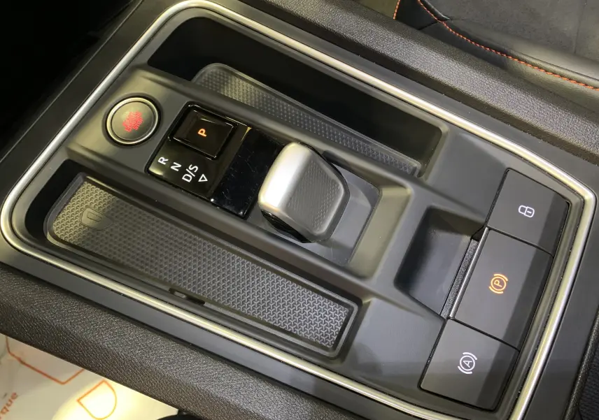 Gros plan sur la console centrale grise de la SEAT LEON E-HYBRID 204 FR DSG6 avec levier de vitesse et boutons de commande.