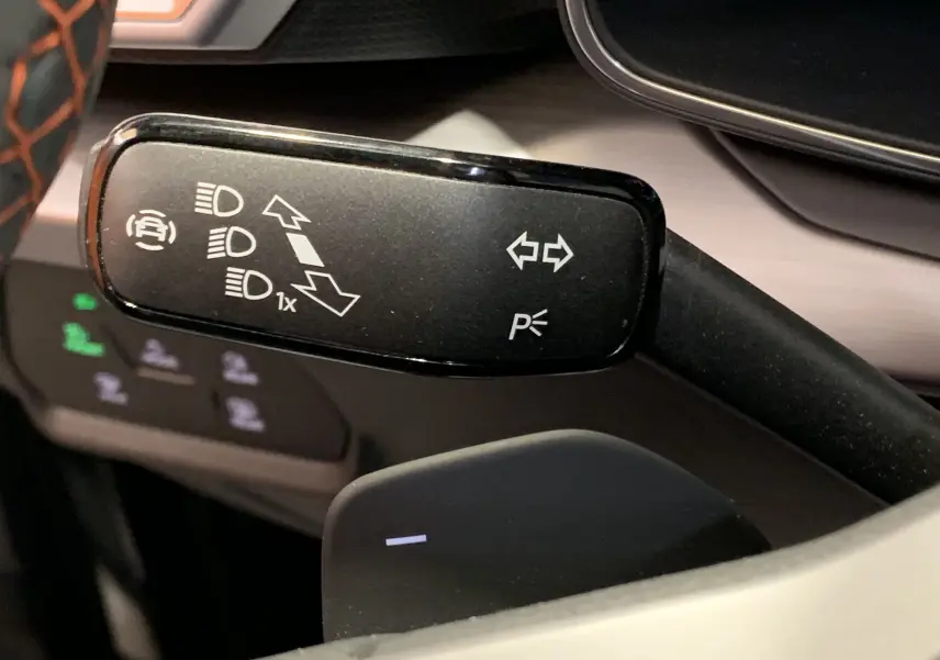 Gros plan sur la manette de clignotants noire du SEAT Leon gris 2020, avec symboles blancs de feux et direction.