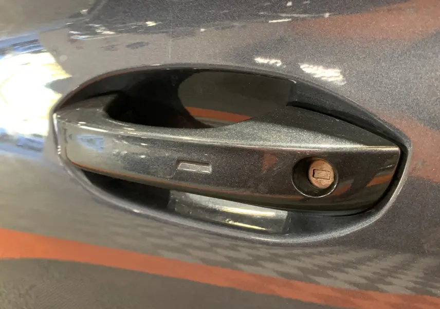 Poignée de porte avant droite gris métallisé d'une SEAT LEON E-HYBRID 204 FR DSG6 de 2020 avec serrure visible.
