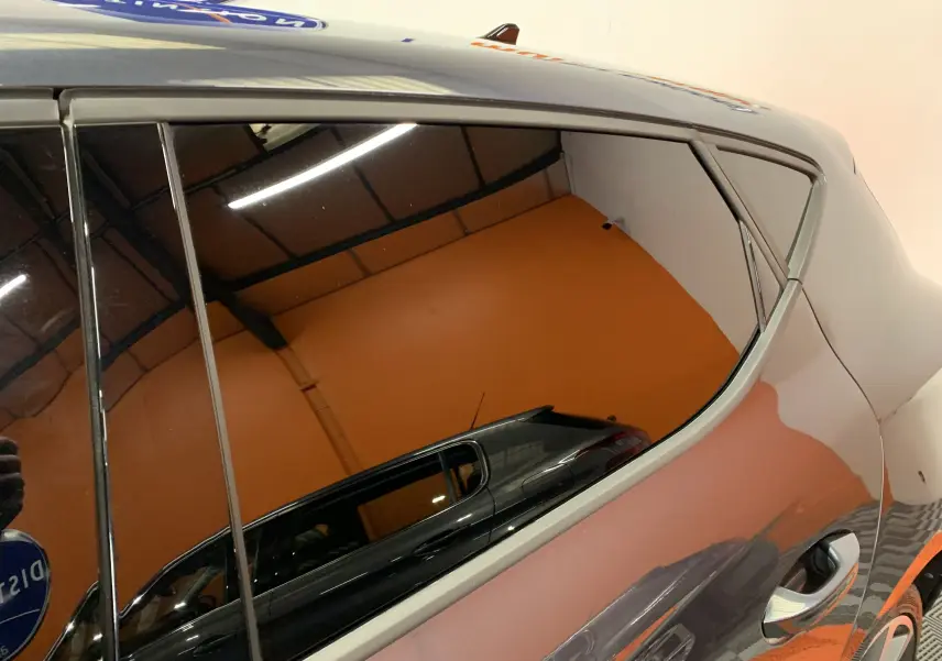 Reflet du côté gauche gris métallisé d'une SEAT LEON E-HYBRID 204 FR DSG6 avec poignée de porte visible.