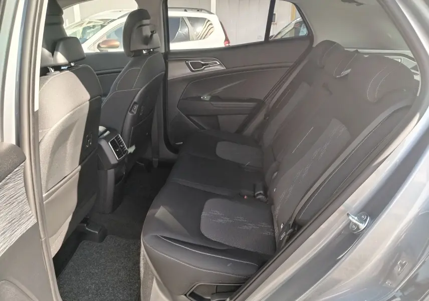 Vue intérieure côté arrière droit du Kia Sportage gris perle 2025, montrant les sièges arrière en tissu noir avec surpiqûres.