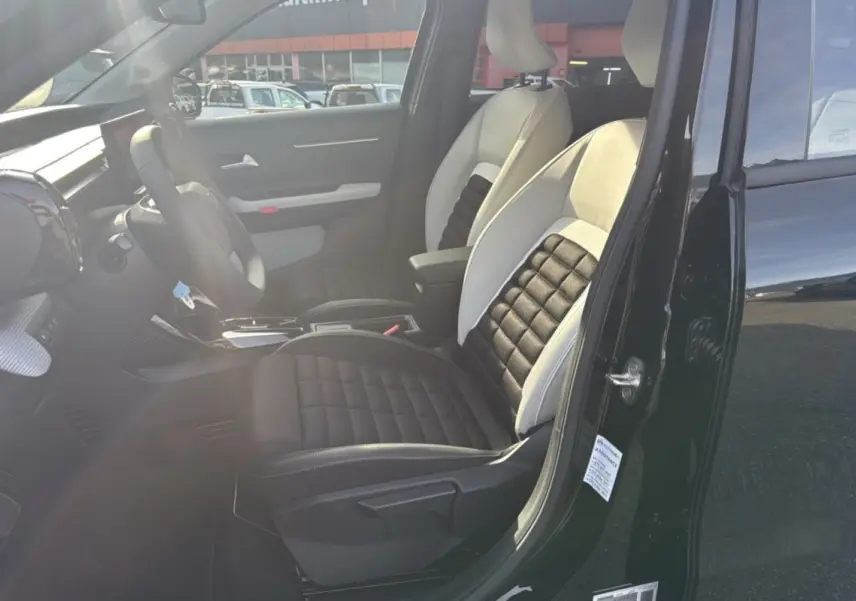 Intérieur côté conducteur d'une Citroën C3 Aircross noir perla nera, siège tissu bicolore avec accoudoir central visible.