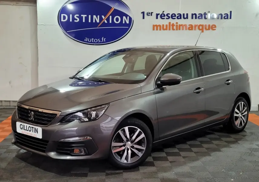 Peugeot 308 gris foncé vue 3/4 avant droit dans un showroom avec logo Distinxion en arrière-plan.