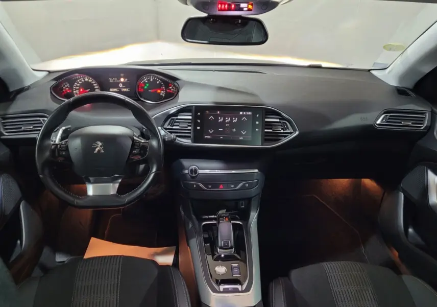 Vue intérieure avant du tableau de bord et volant cuir noir de la Peugeot 308 gris foncé avec écran tactile central.