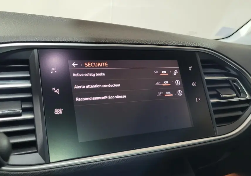 Écran tactile central affichant les réglages de sécurité dans l’habitacle d’une Peugeot 308 gris foncé, vue de face.