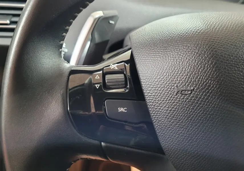 Gros plan sur le côté gauche du volant cuir noir de la Peugeot 308 2020 avec commandes audio intégrées.