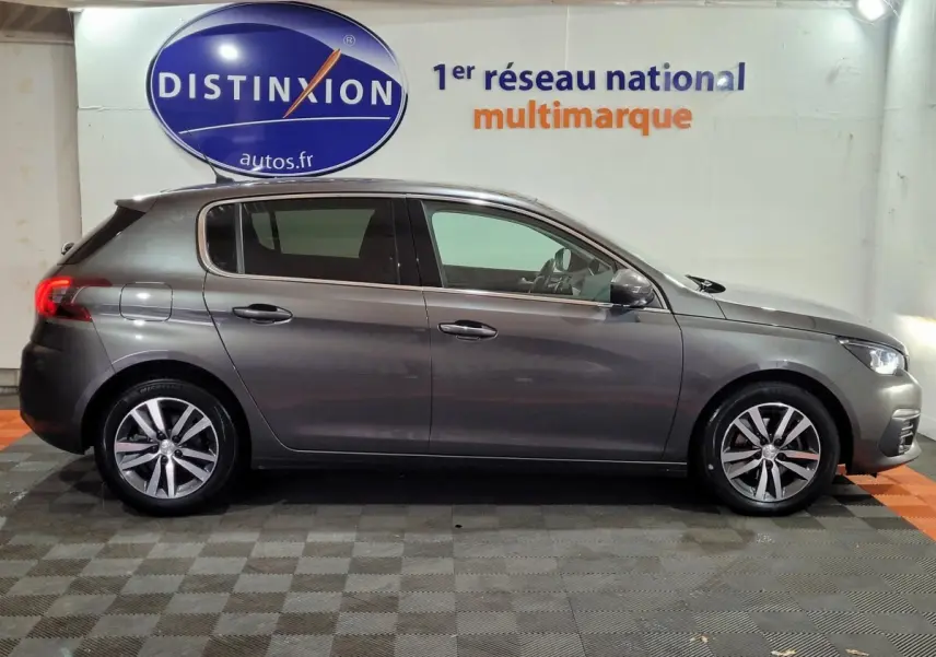 Profil droit d'une Peugeot 308 gris foncé 2020 garée en intérieur avec jantes alliage et vitres teintées.