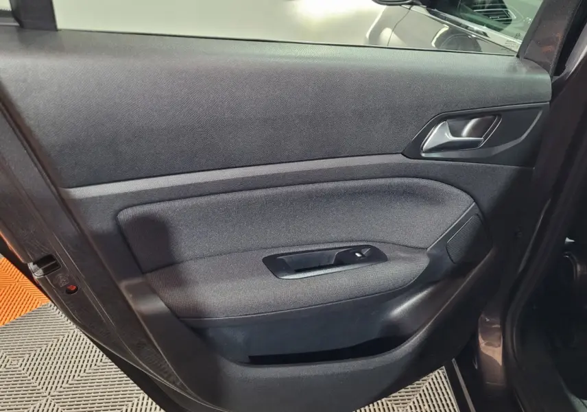 Porte intérieure côté gauche en tissu noir de la Peugeot 308 BlueHDi 130 gris foncé, avec poignée et commande vitre.