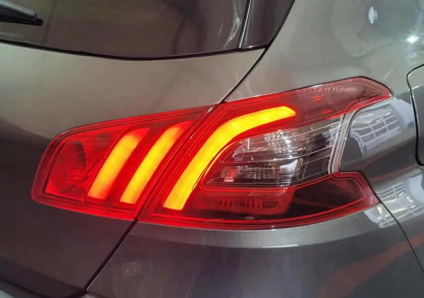 Gros plan sur le feu arrière droit allumé d'une Peugeot 308 gris foncé, version BlueHDi 130 de 2020.