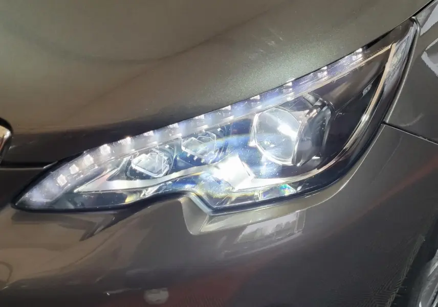 Gros plan sur le phare avant droit LED d'une Peugeot 308 gris foncé, soulignant ses détails lumineux modernes.