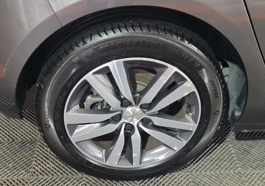 Gros plan sur la roue avant gauche de la Peugeot 308 gris foncé, avec jante alliage et pneu Michelin.