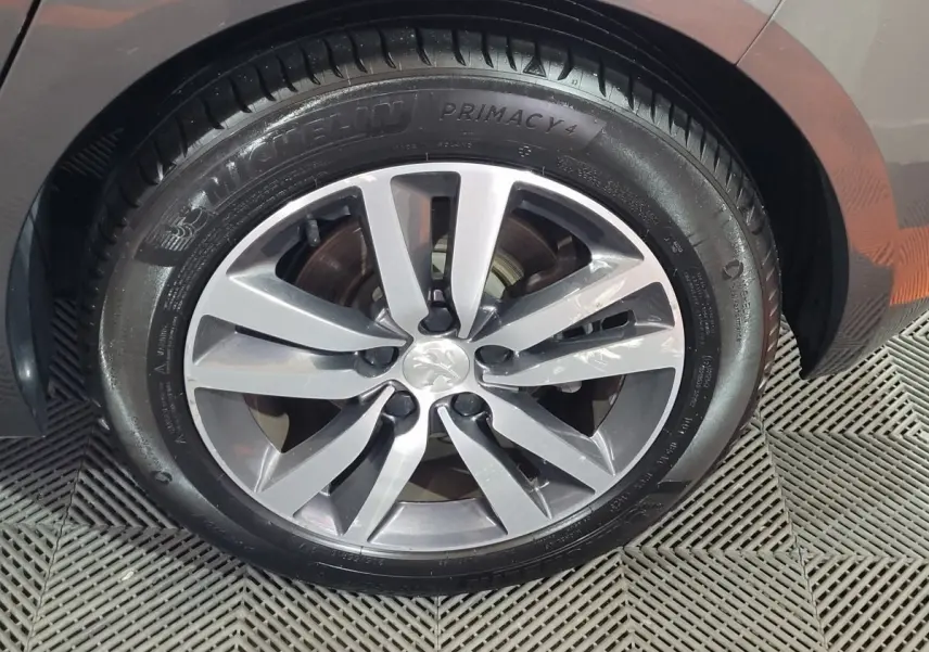 Gros plan sur la jante alliage gris et pneu Michelin d'une Peugeot 308 gris foncé, côté arrière droit.