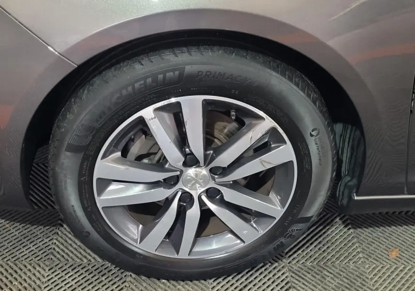 Gros plan sur la roue avant gauche d'une Peugeot 308 gris foncé, avec jante alliage et pneu Michelin Primacy 4.