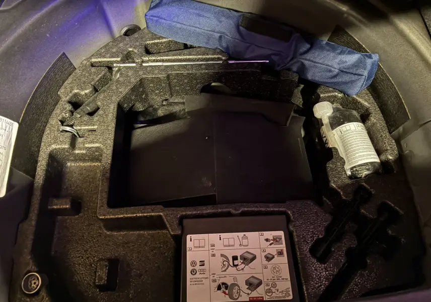 Vue rapprochée du coffre d’un Audi A1 noir 2016 montrant le rangement en mousse avec outils et kit de réparation pneus.