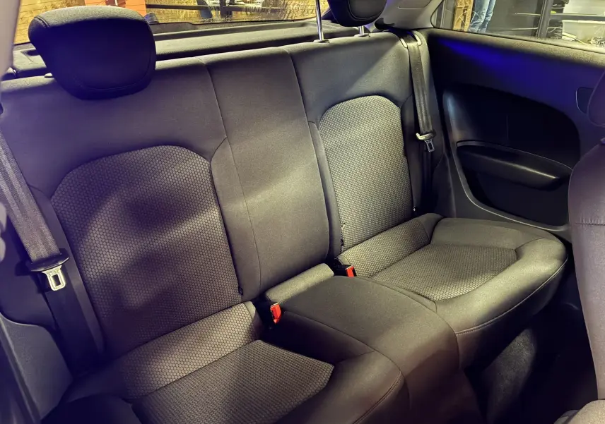 Vue intérieure arrière de l'Audi A1 2016, sièges en tissu gris noir avec ceinture de sécurité et appuie-têtes visibles.