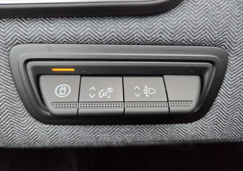 Gros plan sur les commandes d’éclairage et de régulateur de vitesse sur tableau de bord gris texturé d’une Renault Clio 2025.