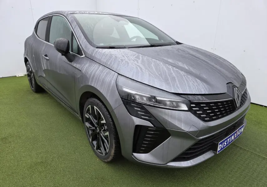 Renault Clio V gris schiste métal vue 3/4 avant gauche avec jantes alliage noires et phares LED distinctifs.