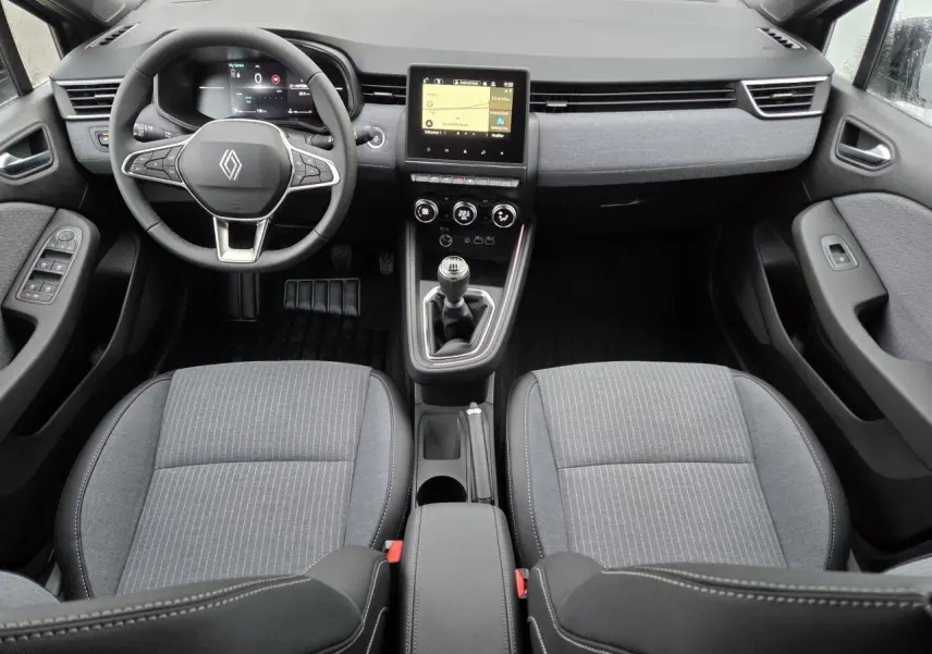 Vue intérieure avant de la Renault Clio 2025 gris schiste, avec volant multifonction, écran tactile et boîte manuelle.