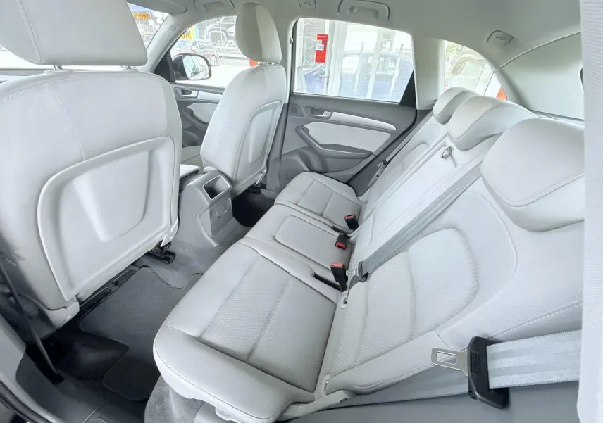 Vue intérieure arrière côté droit montrant les sièges arrière gris clair et les dossiers des sièges avant d’un Audi Q5 noir.