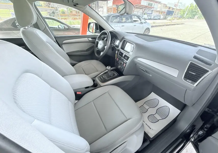 Vue intérieure côté passager de l'Audi Q5 2014 noire, montrant sièges gris clairs et tableau de bord moderne.