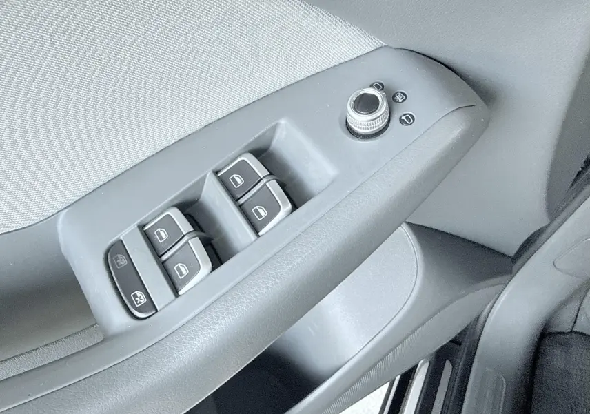 Gros plan sur les commandes des vitres et rétroviseurs côté conducteur d’un Audi Q5 noir de 2014.