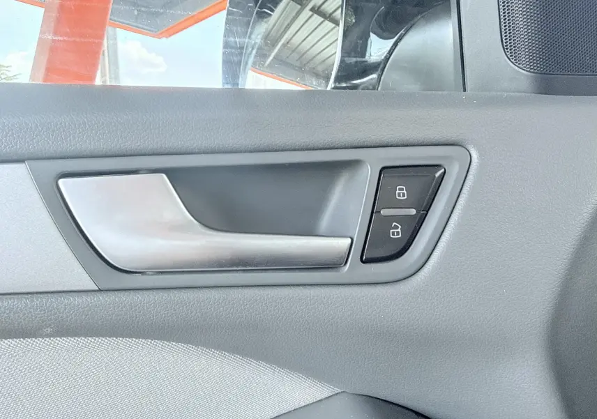 Poignée intérieure de porte côté gauche de l'Audi Q5 noire, avec boutons de verrouillage visibles.