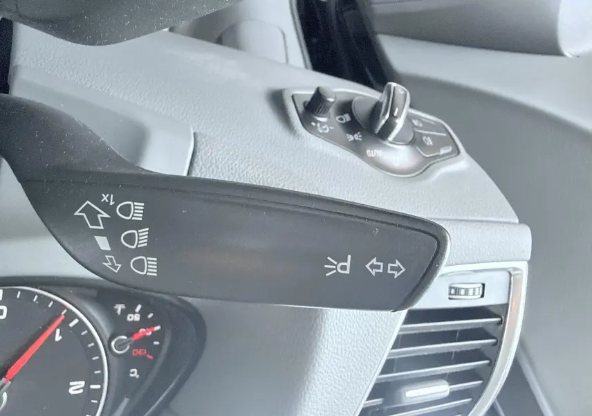 Gros plan sur la commande des clignotants et phares à gauche du volant dans l’habitacle noir de l’Audi Q5 2014.